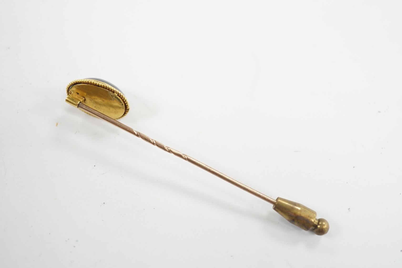 A cased Victorian yellow metal, oval cabochon garnet and diamond chip set stick pin, overall 77mm. Condition - fair